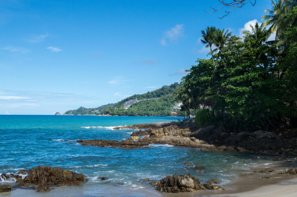 Breathtaking tropical coastline with lush greenery and clear blue sea in Phuket, Thailand.